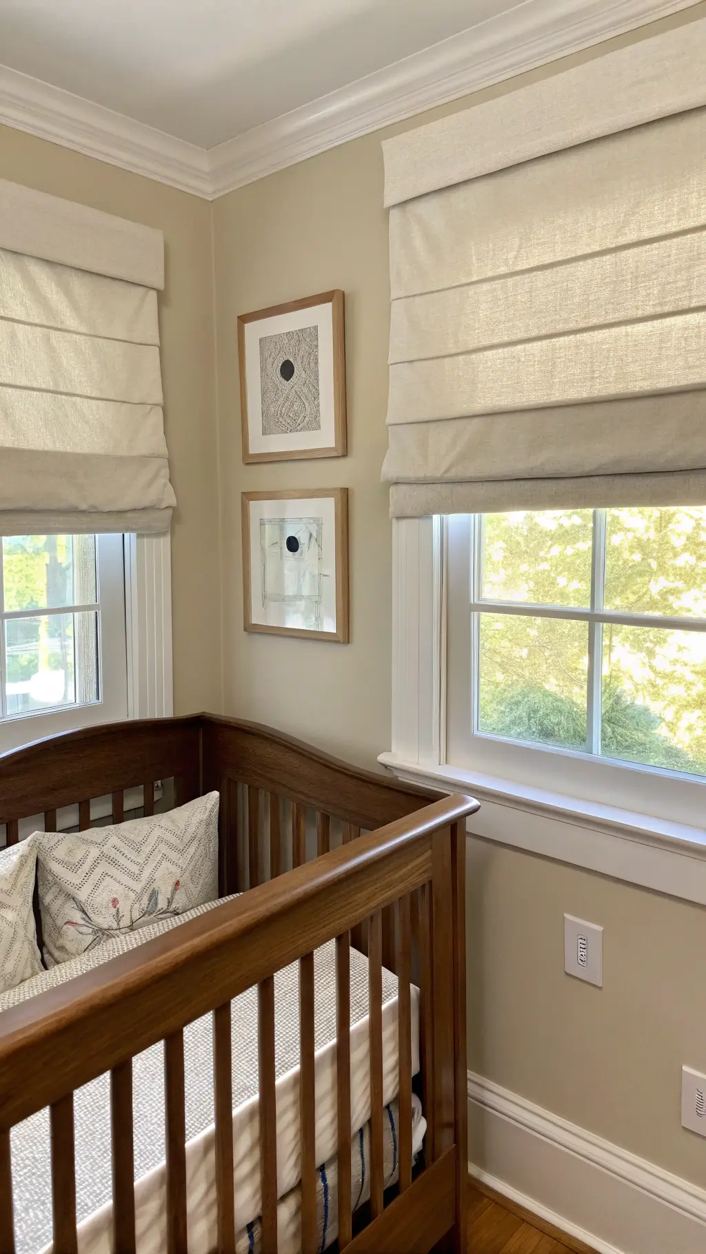 Modern nursery corner with cordless linen roman blinds, childproof outlet covers, rounded built-in furniture, and secure wall mounts in a soft neutral palette.