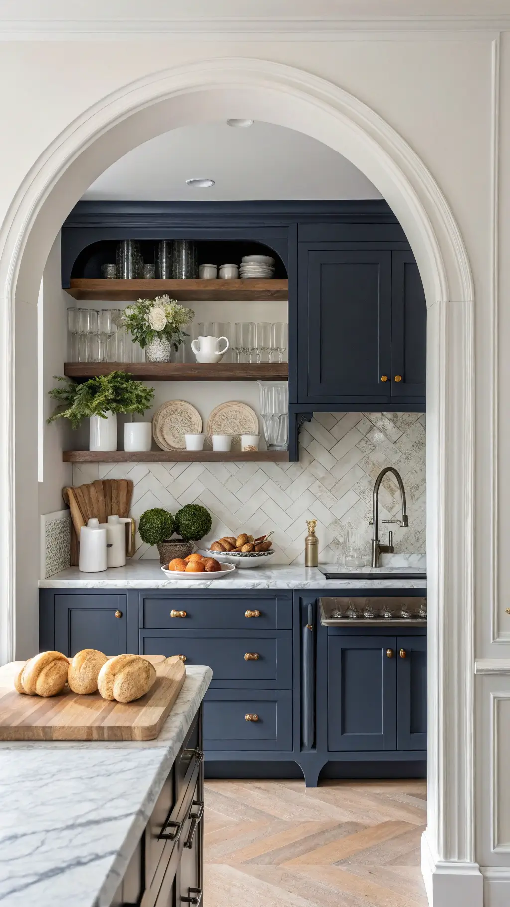 Transitional navy kitchen with marble backsplash, mixed metal accents, and natural morning light highlighting breakfast setup and artisanal decor.